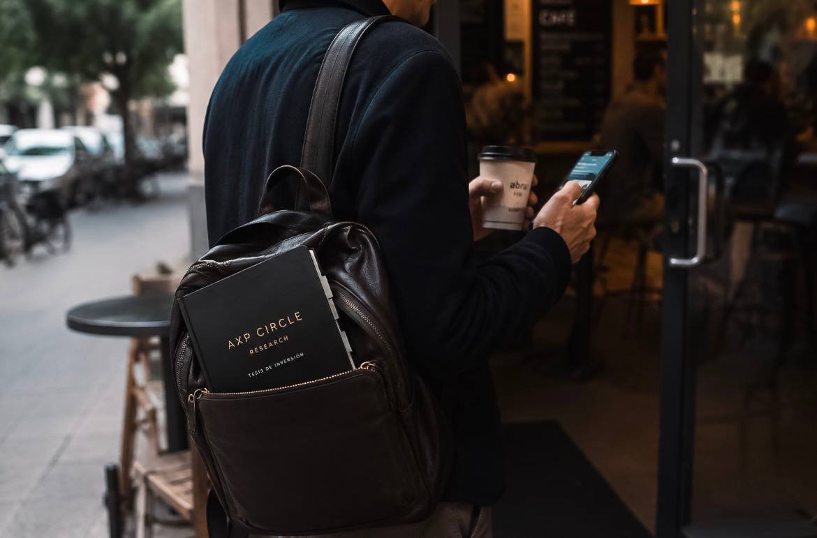 Miembro de AXP CIRCLE llevando una tesis impresa de RESEARCH al entrar a una cafetería.